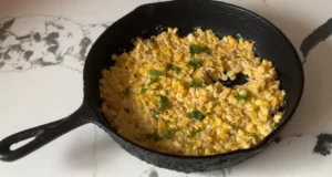 Honey Butter Skillet Corn in a cast iron skillet garnished with fresh herbs.