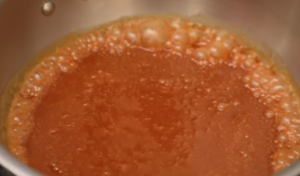 Smooth caramel frosting being spread on a cake with a spatula.