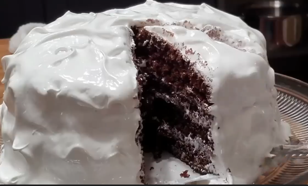 Smooth caramel frosting being spread on a cake with a spatula.