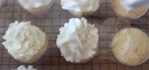 This image shows a freshly whipped batch of buttermilk frosting, smooth and creamy in texture, ready to be spread on cakes or cupcakes. Surrounding the bowl are key ingredients like butter, brown sugar, powdered sugar, and a whisk, highlighting the simplicity of the recipe.