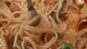 Uncooked fideo and spaghetti pasta side by side on a wooden surface.