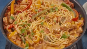 Uncooked fideo and spaghetti pasta side by side on a wooden surface.