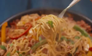 Uncooked fideo and spaghetti pasta side by side on a wooden surface.