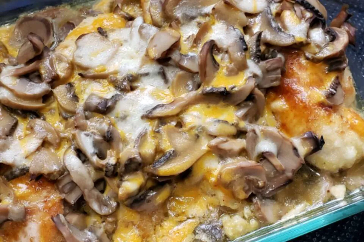 Baked chicken topped with sautéed mushrooms and melted cheese in a glass baking dish.